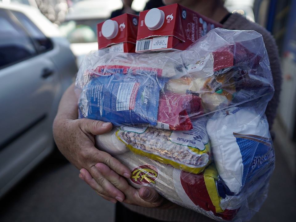 Funcionário recebendo a cesta básica nas mãos